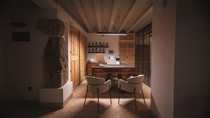 Une cuisine moderne avec des meubles en bois, un mur d’accent en pierre et un coin repas avec deux chaises.