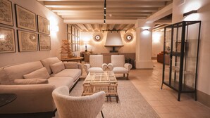 A spacious living room with a beige sofa, two armchairs, a coffee table, and a glass display case. - Hotel Boutique Casona de los Rebolledo (Zújar)