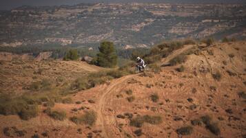 A dirt bike trail winding through a hilly, grassy landscape with sparse trees.