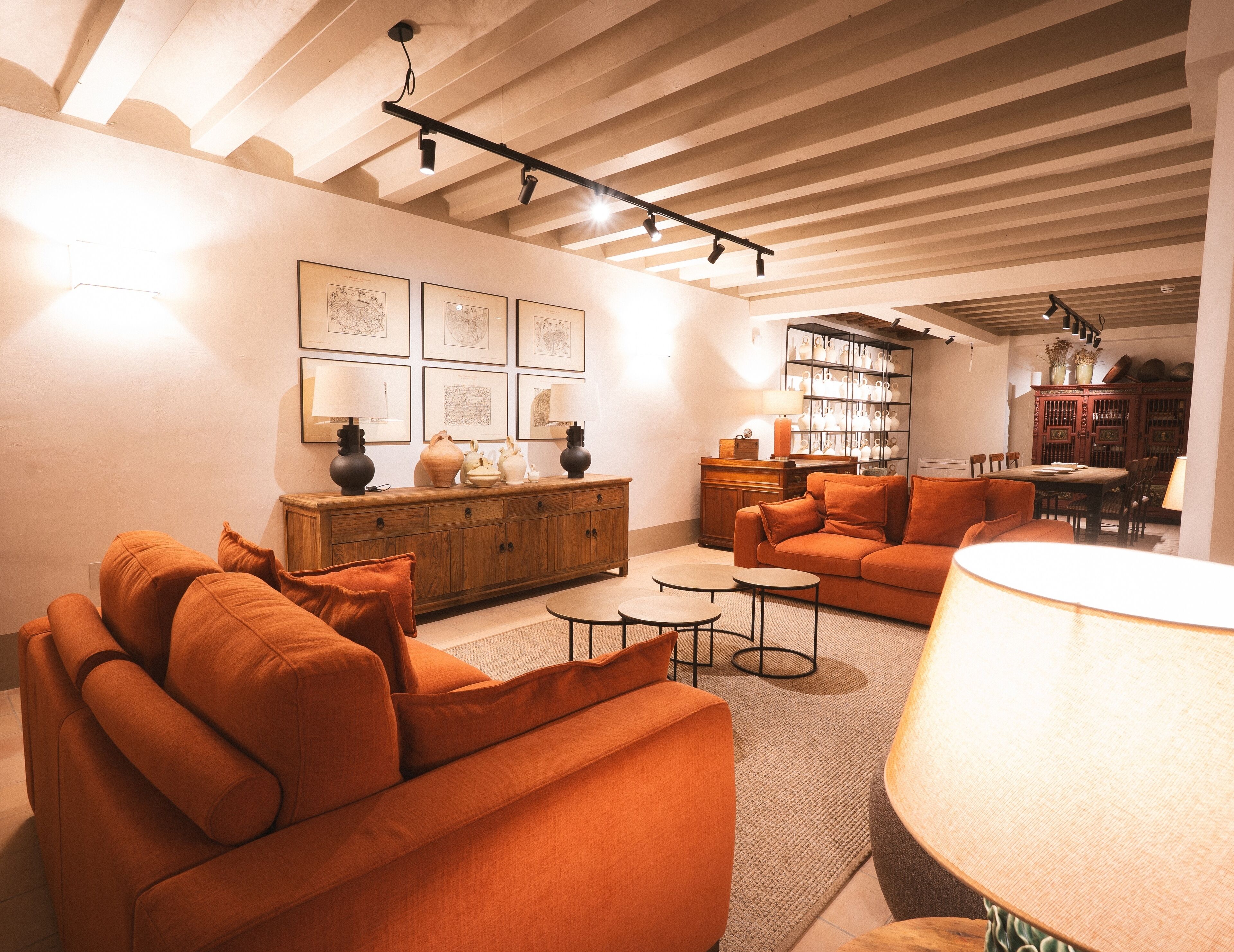 A cozy living room with orange sofas, a wooden cabinet, and a dining area with a table and chairs.