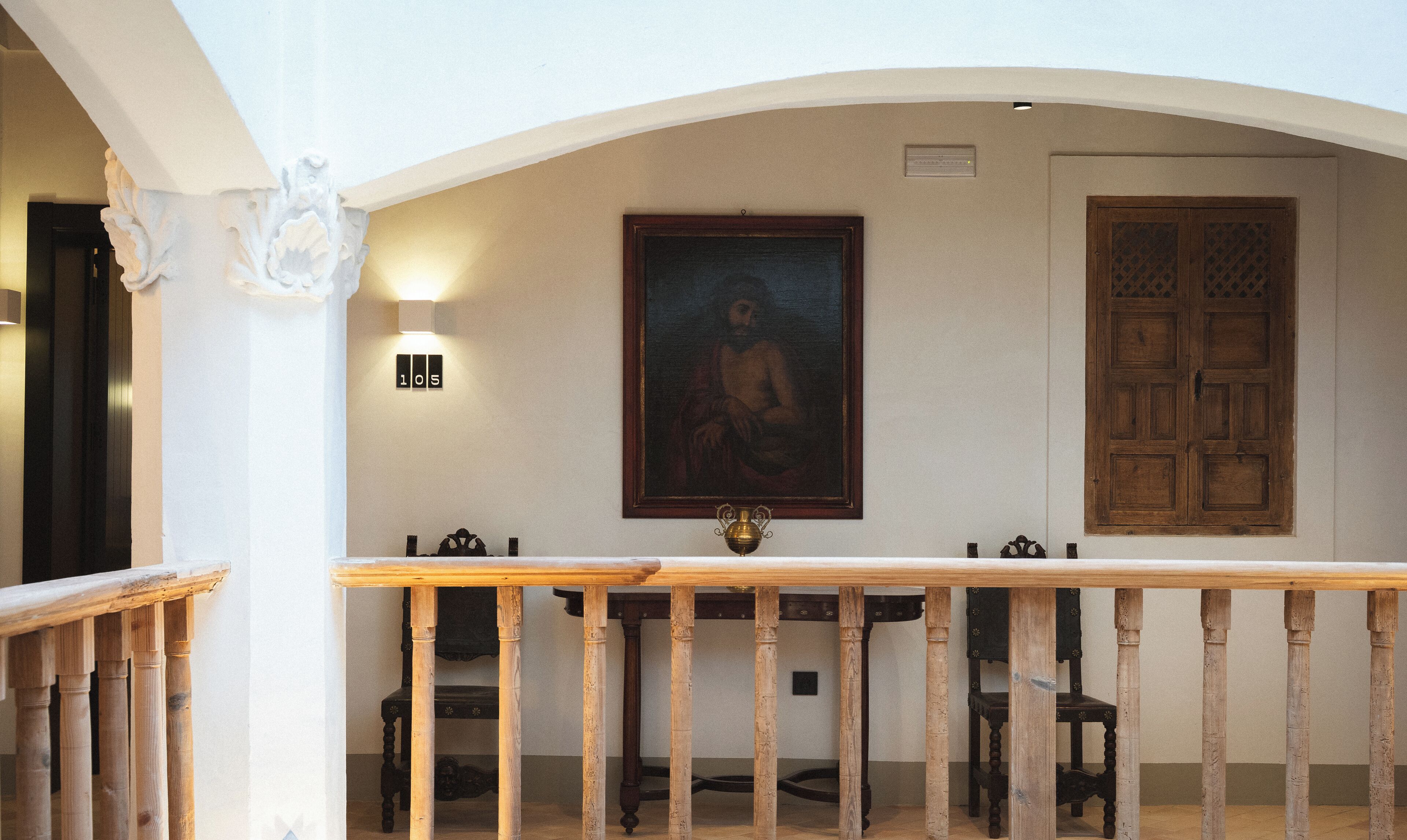 Una habitación con una mesa de madera, sillas, un cuadro y una puerta con un panel decorativo.