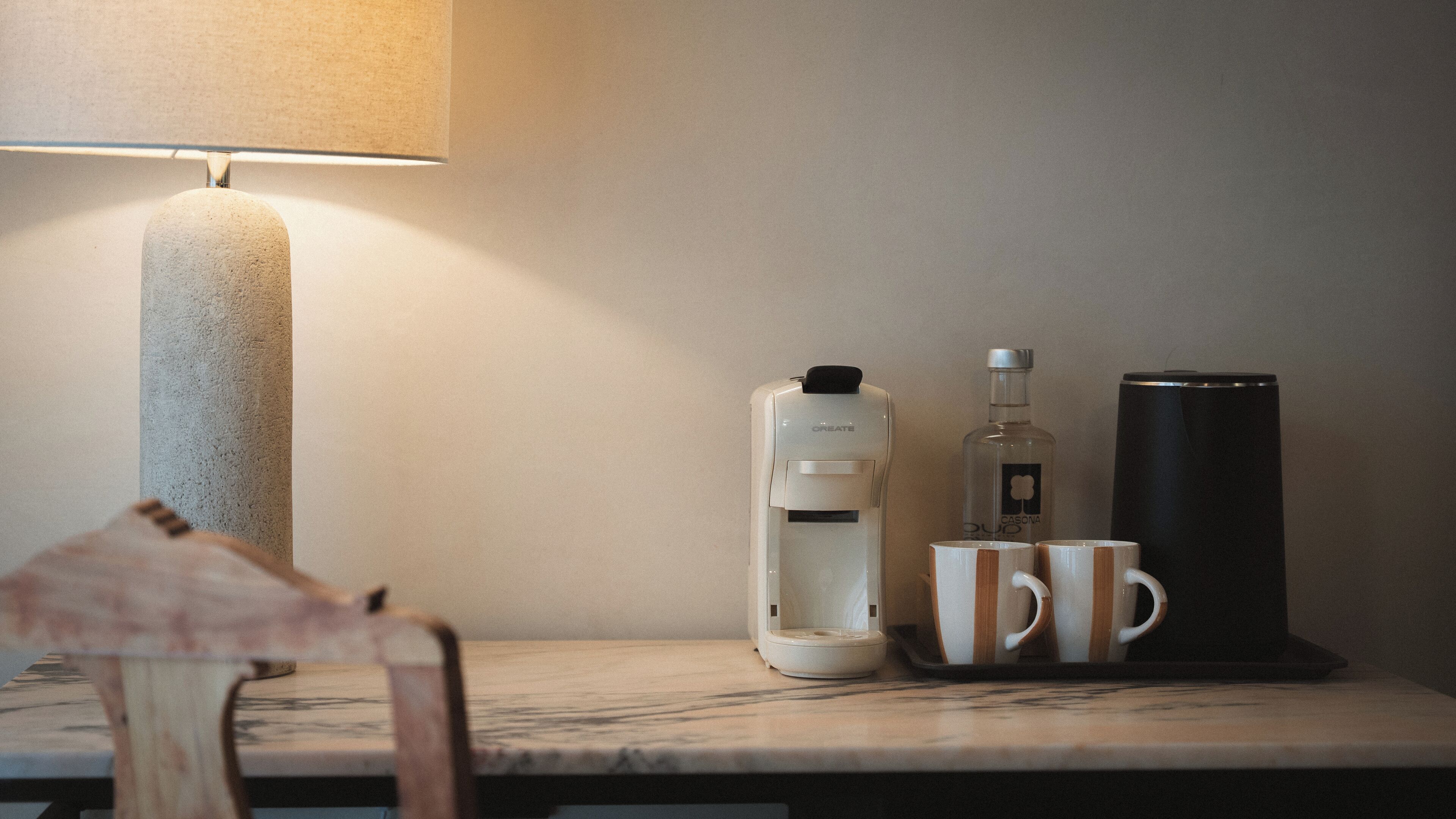 A table with a coffee maker, a water bottle, a mug, and a lamp.