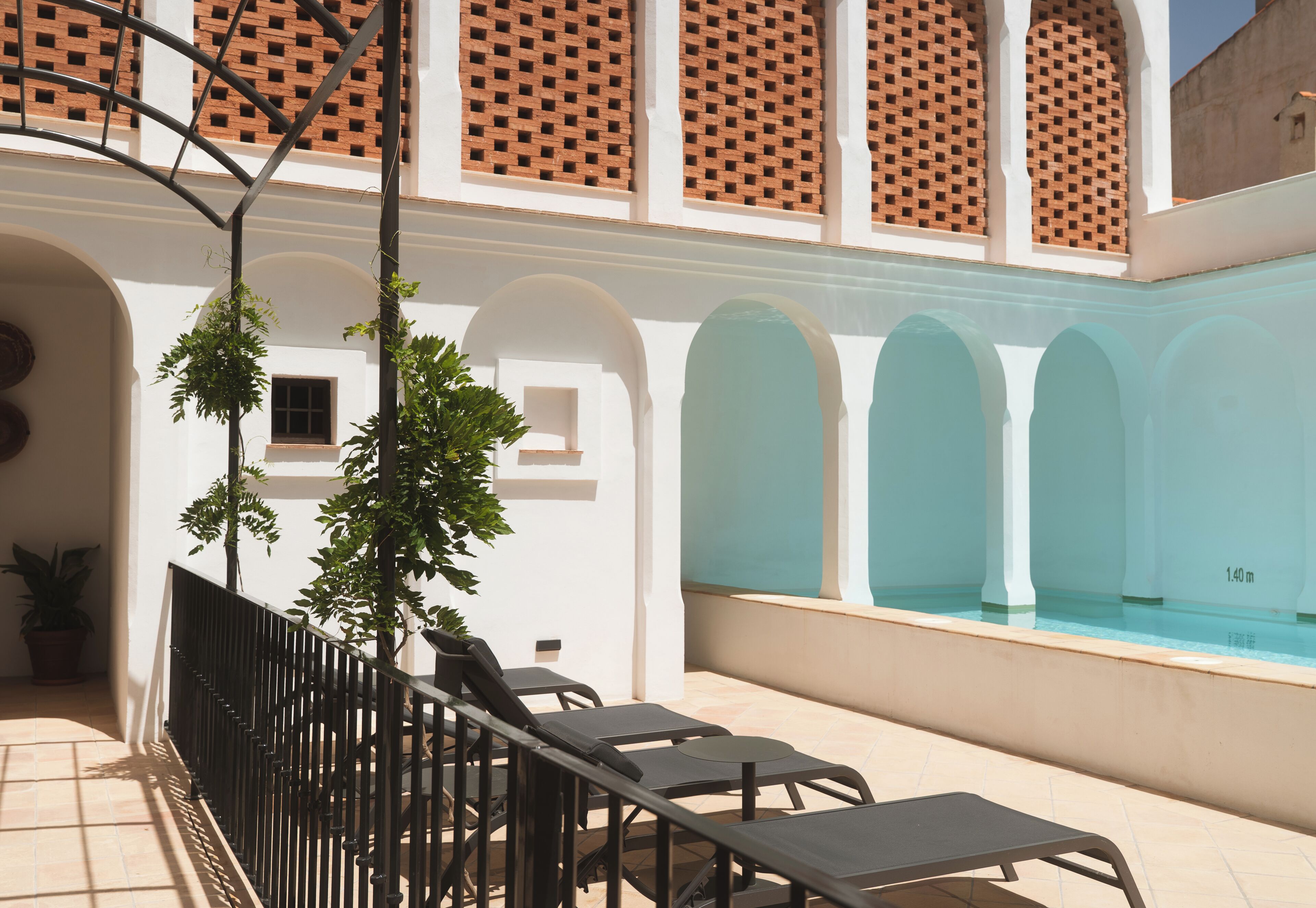 Un área junto a la piscina con sillones de descanso y suelo de baldosas.