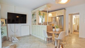 A modern kitchen with white cabinets, a built-in oven, and a dining area with a round table and four chairs. - Modern Beach Retreat 2BR in Coastal Palaio Faliro (Paleo Faliro)