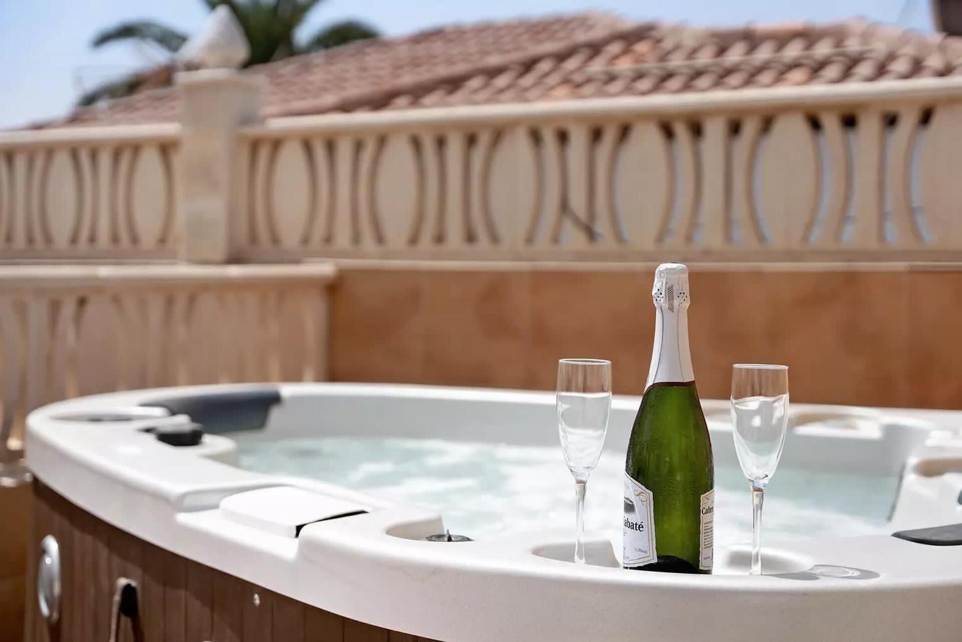 Un jacuzzi con una botella de champán y dos copas.