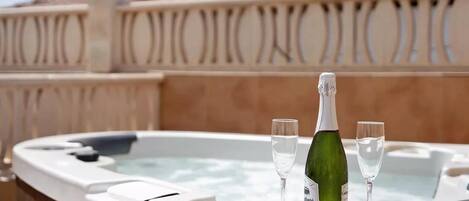 Un jacuzzi con una botella de champán y dos copas.