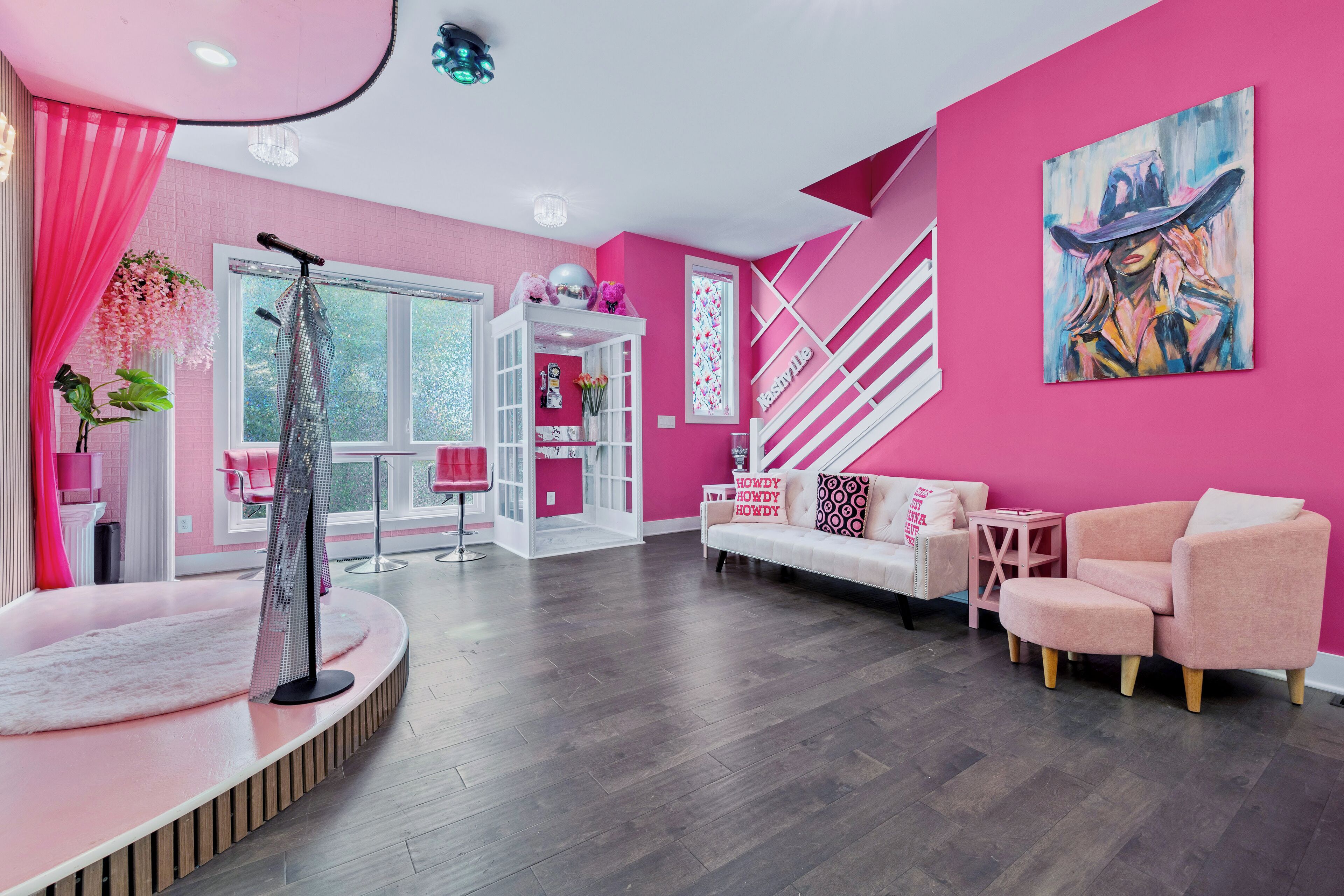 A modern living room with a pink color scheme, a white staircase, and a large window.