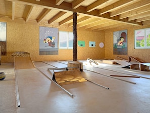 Une pièce avec des poutres en bois, un plafond en pente et un sol parsemé de divers objets.