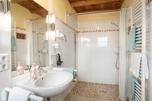 Une salle de bain avec un lavabo, un miroir, une douche et un sol carrelé.