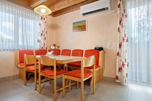 Un coin repas avec une table et des chaises en bois, un tableau au mur et un appareil de climatisation.