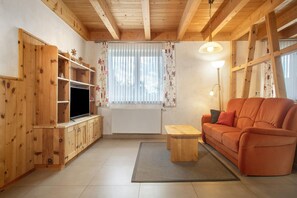 Une pièce aux murs lambrés, avec un canapé, un téléviseur et une lampe.