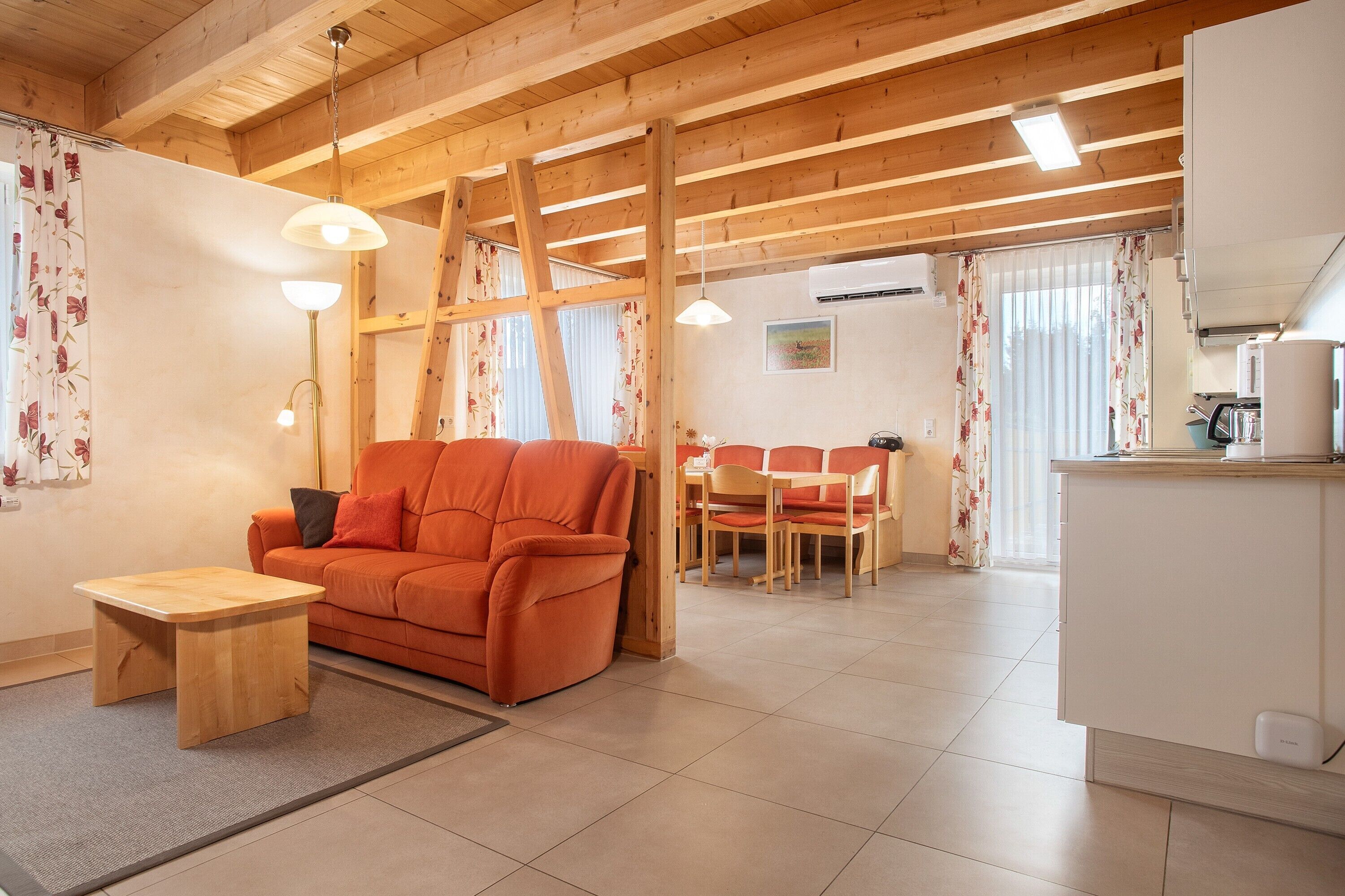A cozy living area with a sofa, a small table, a dining set, and a kitchen area.