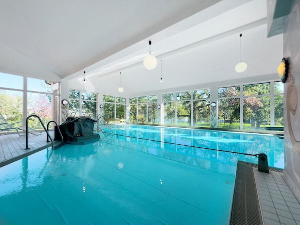 An indoor swimming pool with clear windows, a diving board, and a water slide.