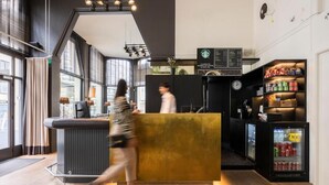 A modern hotel lobby with a reception desk, a clock, and a refrigerator stocked with beverages. - Relaxing Room with Kitchenette | Quick Access to Local Attractions (Oostende)