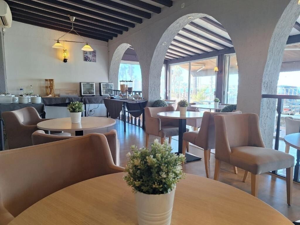 Un intérieur de restaurant moderne, avec des tables rondes, des sièges confortables et de grandes fenêtres.