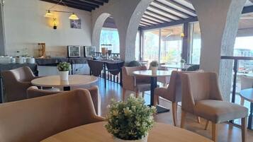 Un intérieur de restaurant moderne, avec des tables rondes, des sièges confortables et de grandes fenêtres.