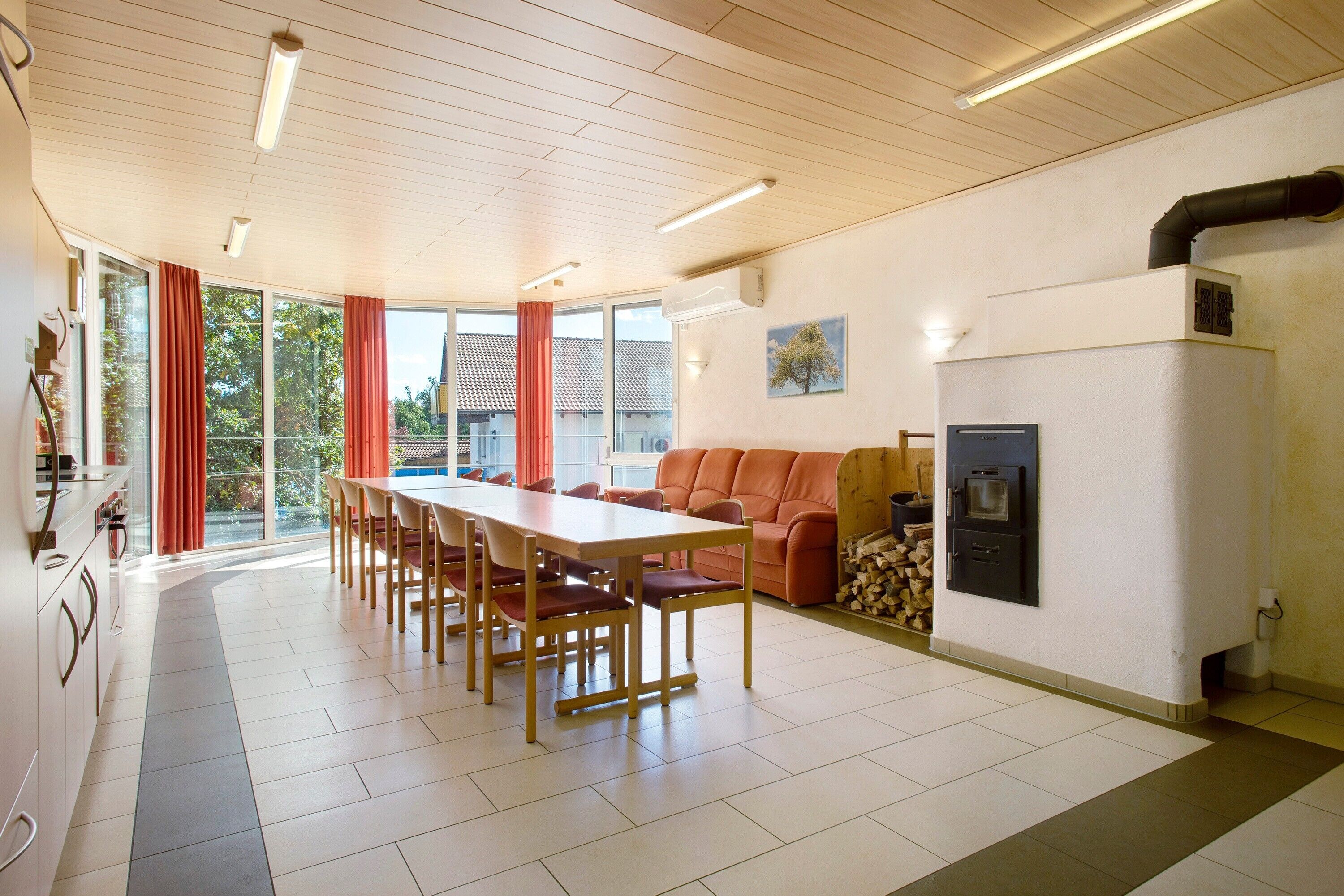 A spacious dining area with a long table and chairs, a sofa, and a wood stove.
