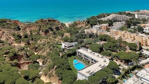 An aerial view of a coastal area with a swimming pool, buildings, and cliffs.