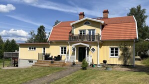 A two-story house with a red-tiled roof, a balcony, and a front porch.