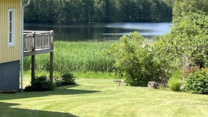A house with a deck overlooking a lake, surrounded by lush greenery.