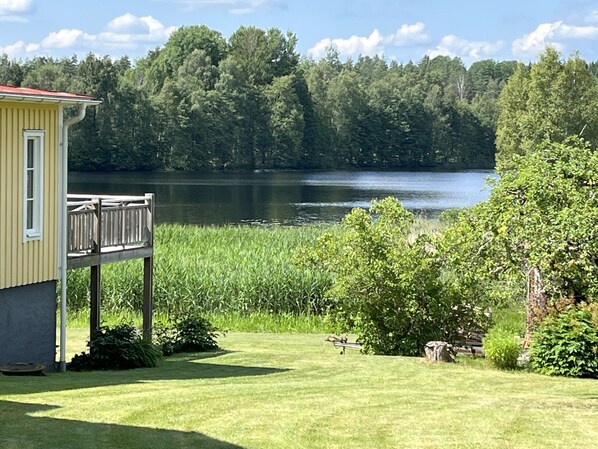 Una casa con terraza que da a un lago, rodeada de abundante vegetación.