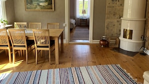 A dining area with a wooden table and chairs, a painting on the wall, and a large white water heater.