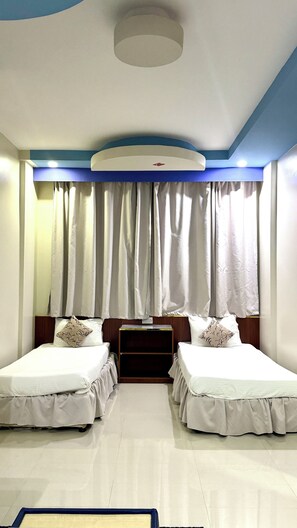 A hotel room with two beds, a wooden headboard, a ceiling light, and a window with curtains. - Dancenter Muscat Holiday Luxury Stay (Seeb)