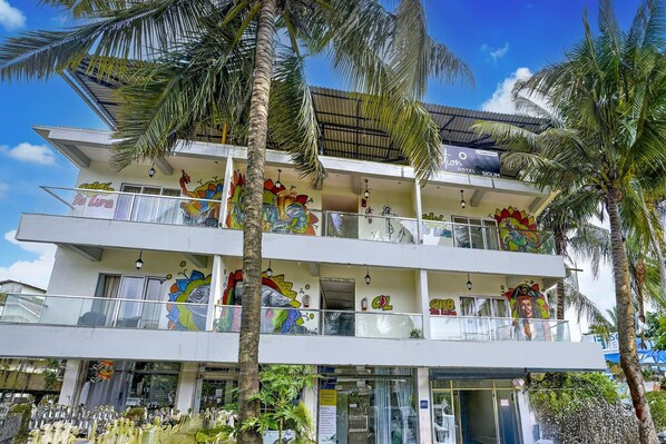 A multi-story hotel with balconies, palm trees, and colorful murals.