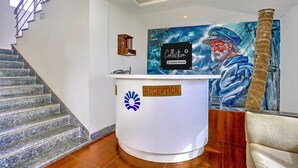 A reception desk with a 'Collection' sign, a staircase, and a mural of a seascape. - Classic Celeb Da Luna (Chopdem)