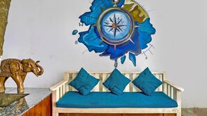 A room with a wooden bench, blue cushions, a wall-mounted compass artwork, and a golden elephant sculpture. - Classic Celeb Da Luna (Chopdem)