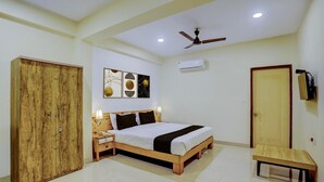 A bedroom with a wooden bed, a wardrobe, a bedside table, a ceiling fan, and an air conditioning unit. - Classic Celeb Da Luna (Chopdem)