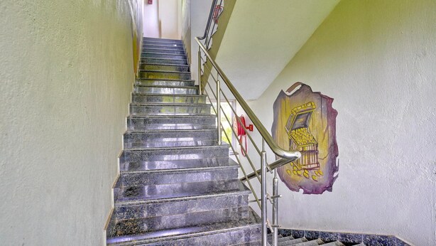 A staircase with metal railings and a wall with a yellow and purple mural. - Classic Celeb Da Luna (Chopdem)