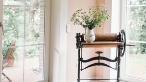A room with a bench, a vase with flowers, and a window with a view of trees. - Holiday Home 'Kleinod' with Mountain View, Shared Terrace and Wi-Fi (Naumburg)