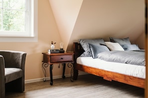 A bedroom with a wooden bed, a nightstand with a lamp, a chair, and a window with a view of trees. - Holiday Home 'Kleinod' with Mountain View, Shared Terrace and Wi-Fi (Naumburg)