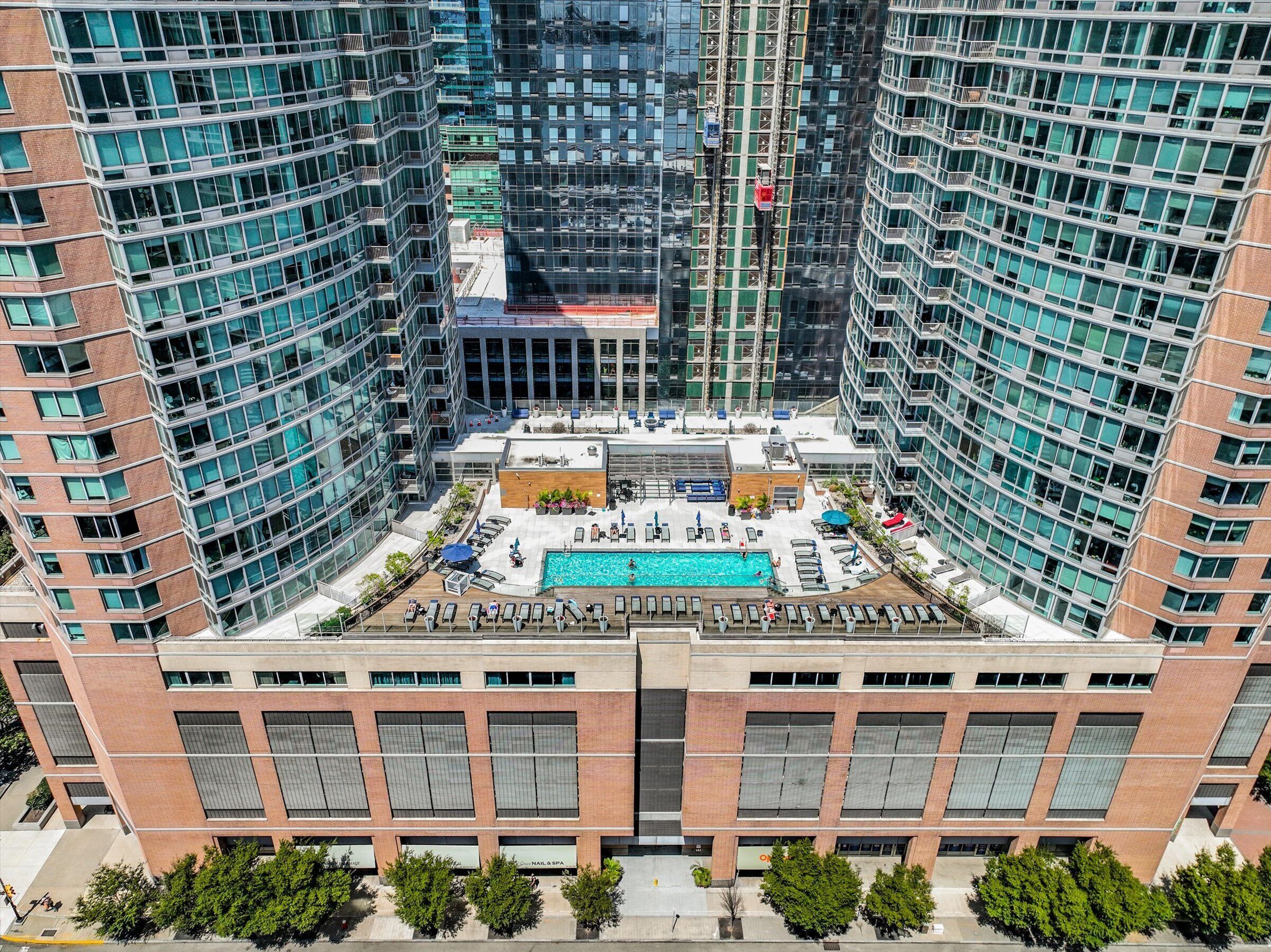 A high-rise building with a rooftop pool, multiple balconies, and a modern architectural design.