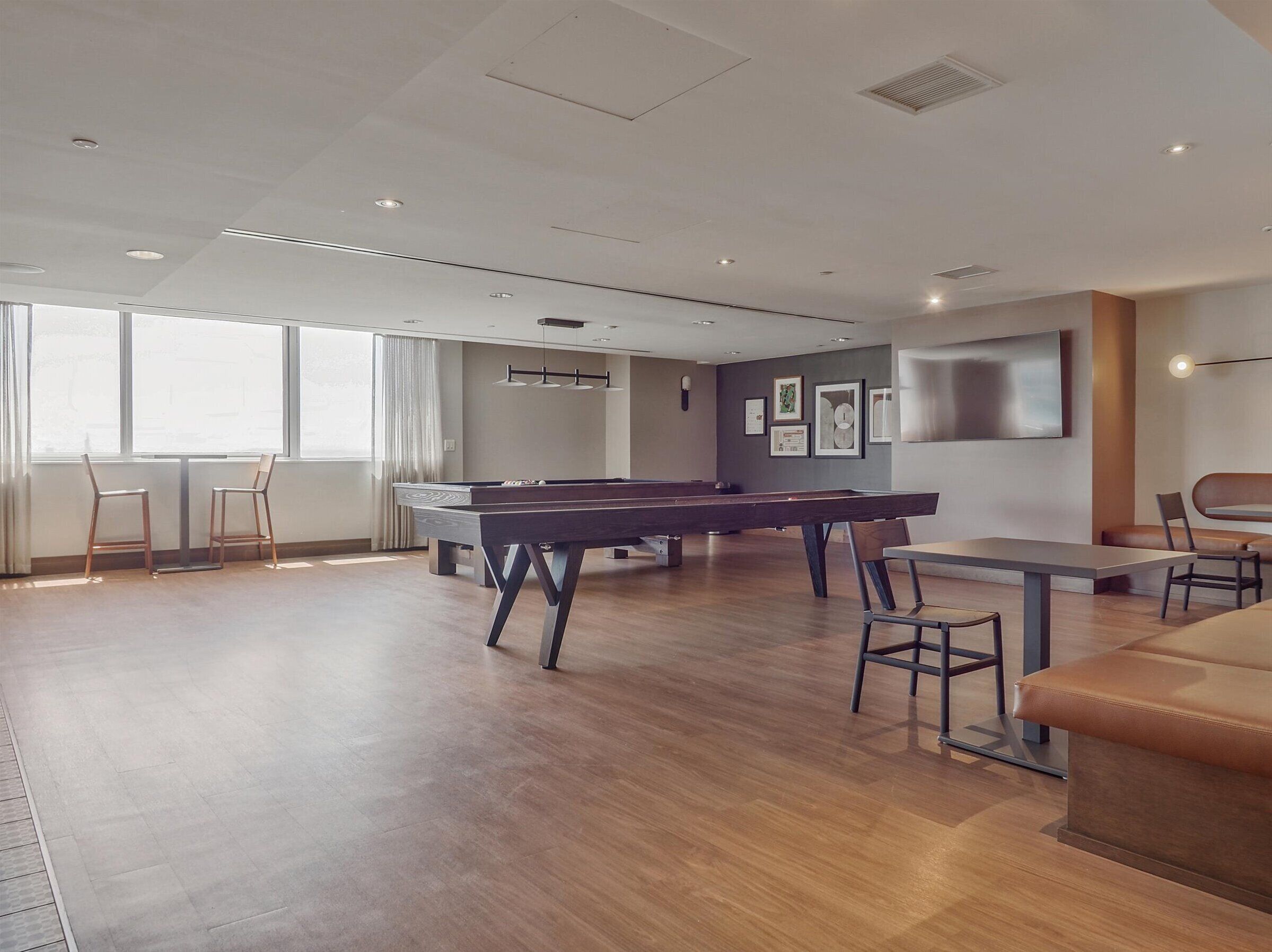 A spacious room with a pool table, a sofa, and a dining table.