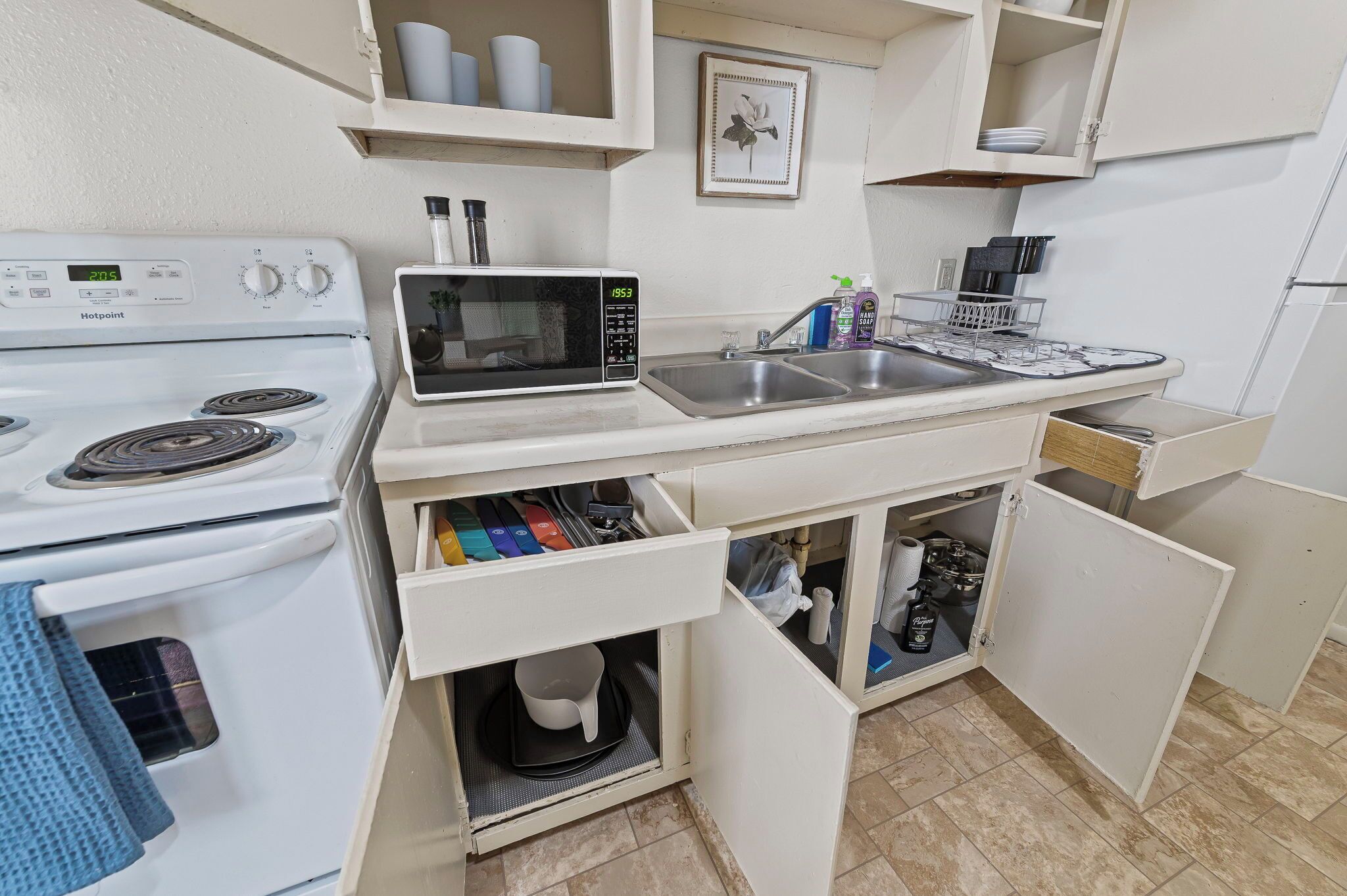 Een kleine keuken met een wit fornuis, magnetron en spoelbak.