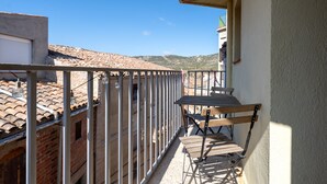 Ein Balkon mit Metallgeländer, einem Holztisch und einem Stuhl.