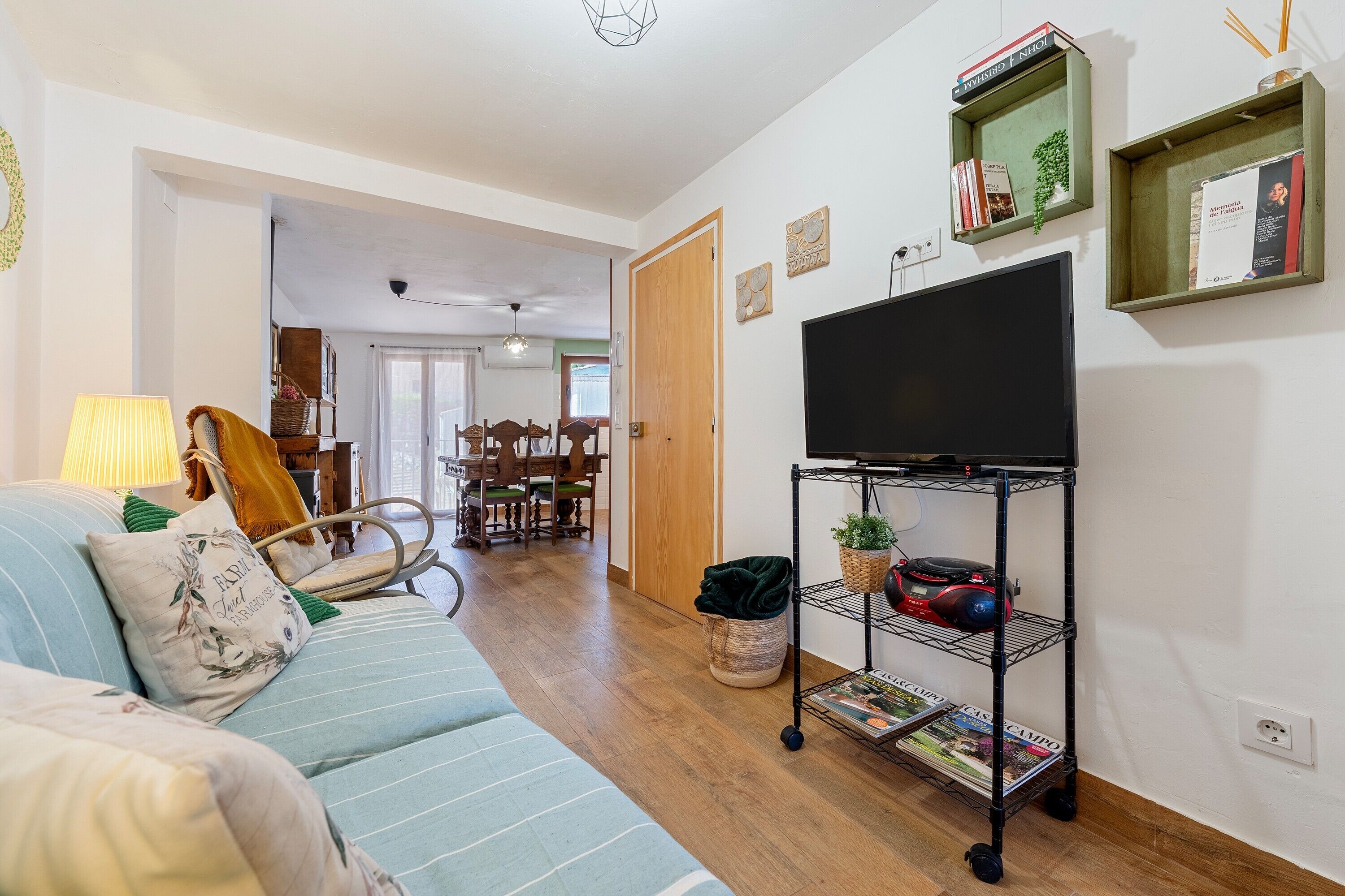 A living room with a sofa, TV, and shelves with books and plants.