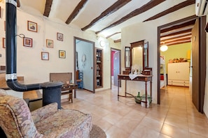 A living room with a sofa, a table, a fireplace, and a kitchen visible through an open door. - Holiday Home 'Tranquil' with Mountain View, Wi-Fi and Air Conditioning (El Lloar)