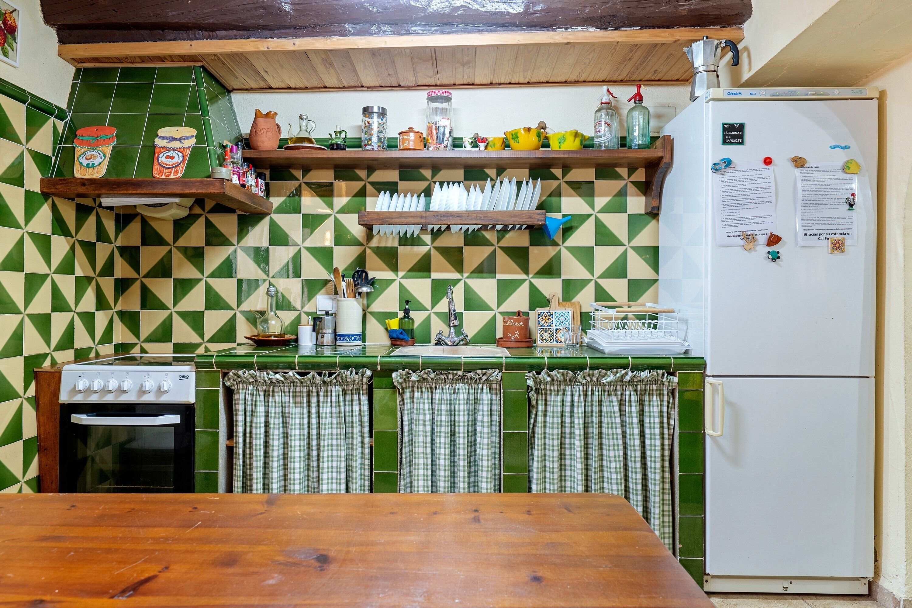 Eine Küche mit einem Herd, Kühlschrank und verschiedenen Küchenutensilien in Regalen.