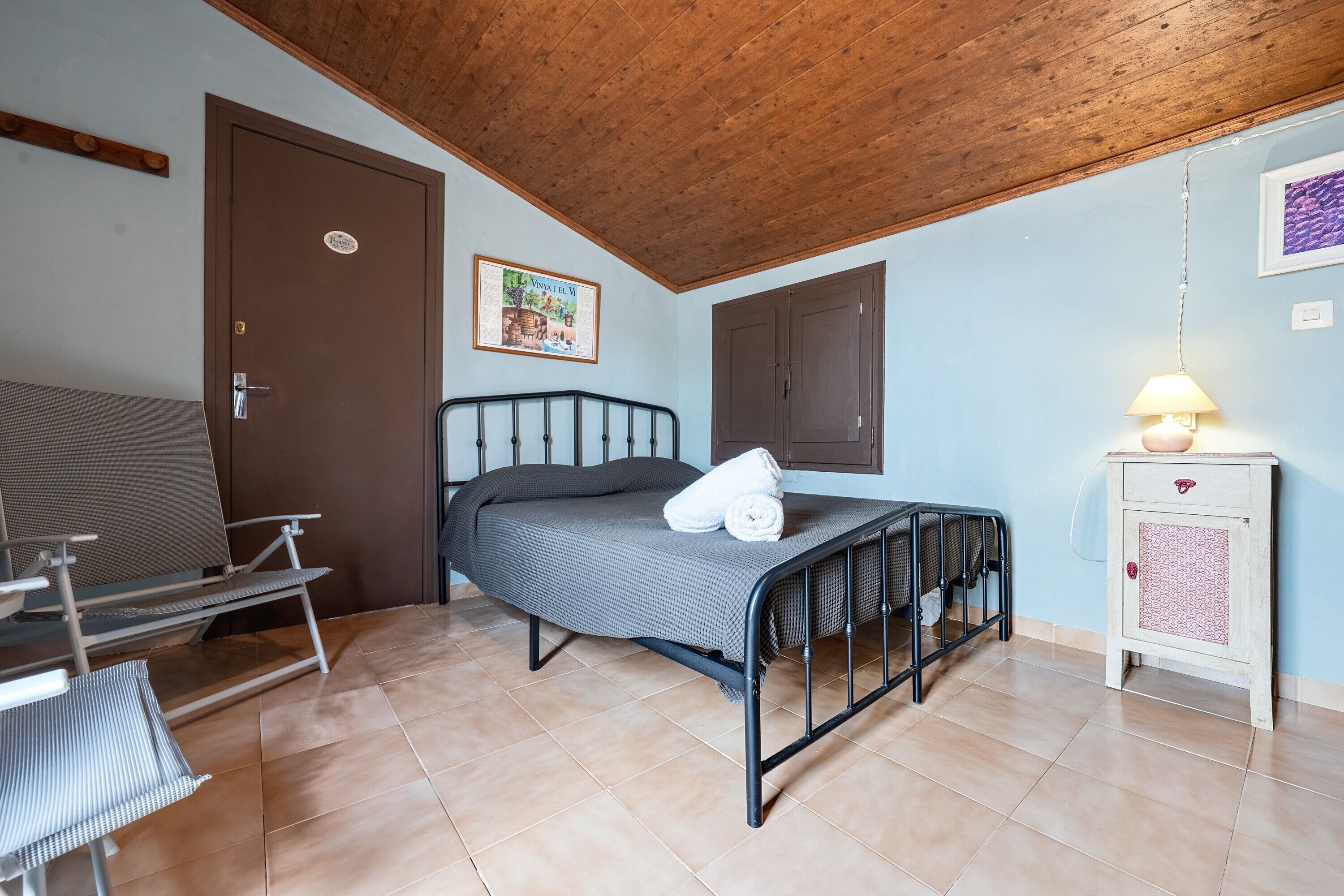 Un dormitorio con cama, una silla, un armario y una puerta.
