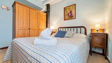 Un dormitorio con cama, armario de madera y mesita de noche con lámpara.