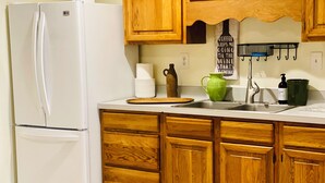 A kitchen with wooden cabinets, a white refrigerator, a sink, and a coffee machine.