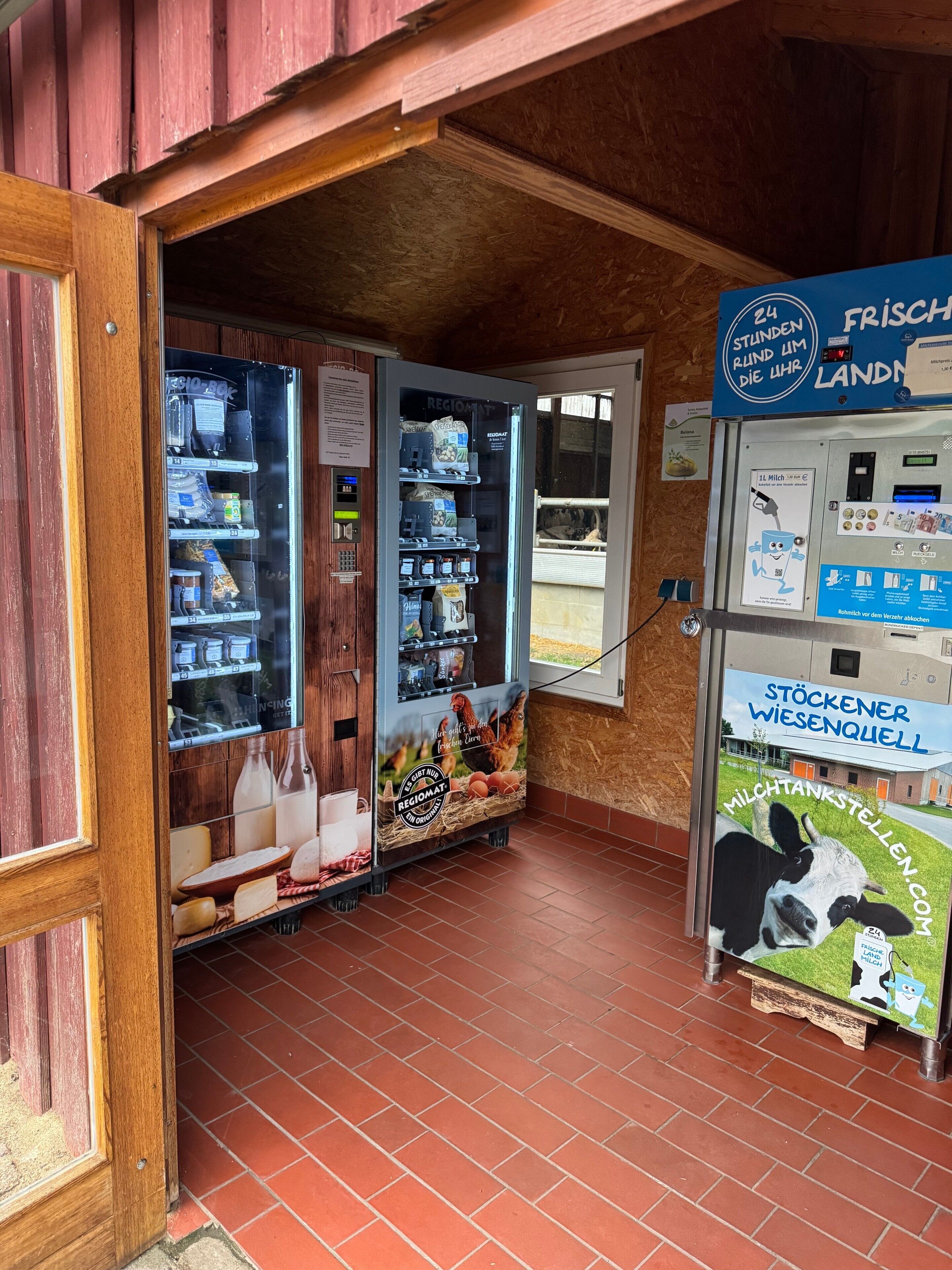 A room with a wooden door, a refrigerator stocked with food, and a milk dispenser.