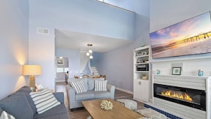Uma sala de estar moderna com lareira, um sofá, uma mesa de centro e um espaço de jantar com cadeiras.