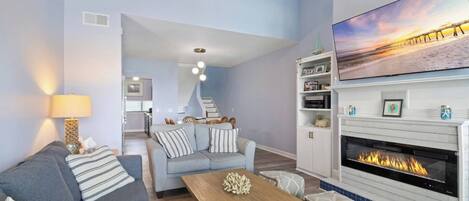 Een moderne woonkamer met een open haard, een bank, een salontafel en een eethoek met stoelen.