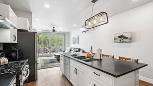 A modern kitchen with a central island, white cabinetry, and a dining area with a table and chairs.