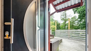 A door with a keyhole and a peephole, leading to an outdoor deck with a wooden railing and a bench. - Apartment 'Kanal' with Private Terrace and Wi-Fi (Steinau)