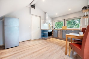 Une cuisine moderne équipée d’un four encastré, d’un réfrigérateur et d’un coin repas avec une table et des chaises.